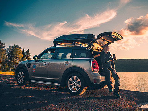 Vediamo un uomo seduto sul bordo del bagagliaio della sua MINI